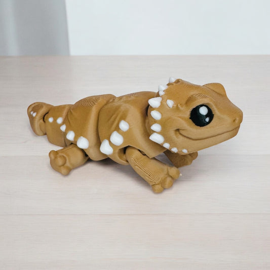 Baby brown 3d printed bearded dragon standing on a wooden surface.