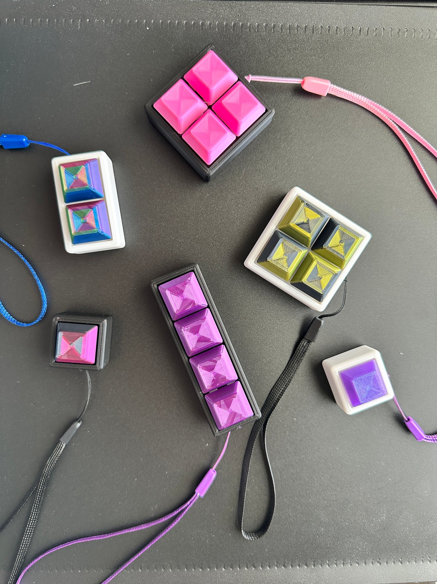 A collection of mechanical keyboard fidget clickers in various colors, attached to keychains, displayed on a table.