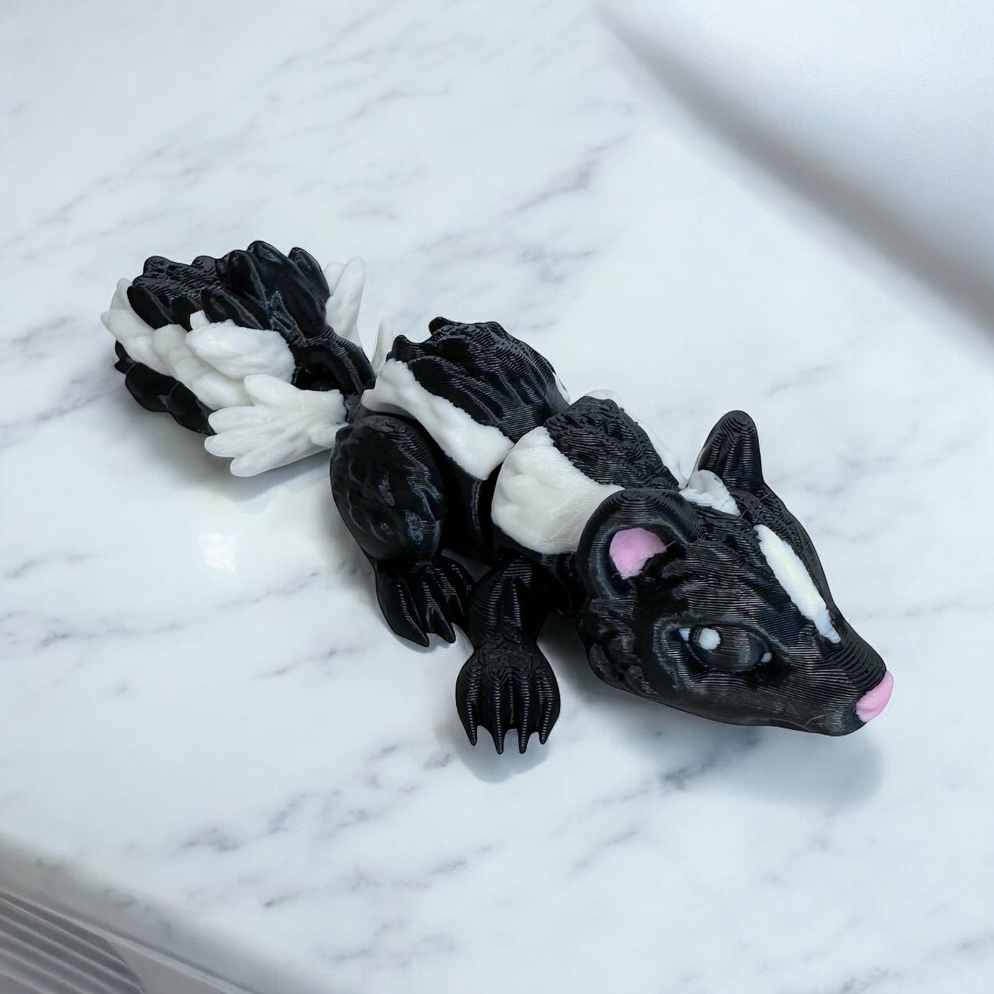 3d printed black and white skunk . On a white marble surface.