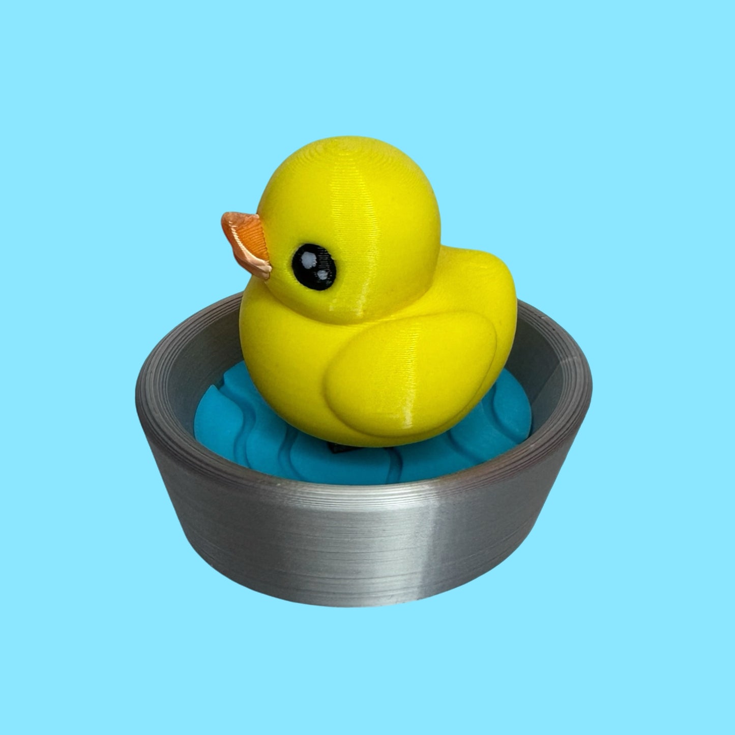 3d printed duck clicker fidget toy against a blue background.