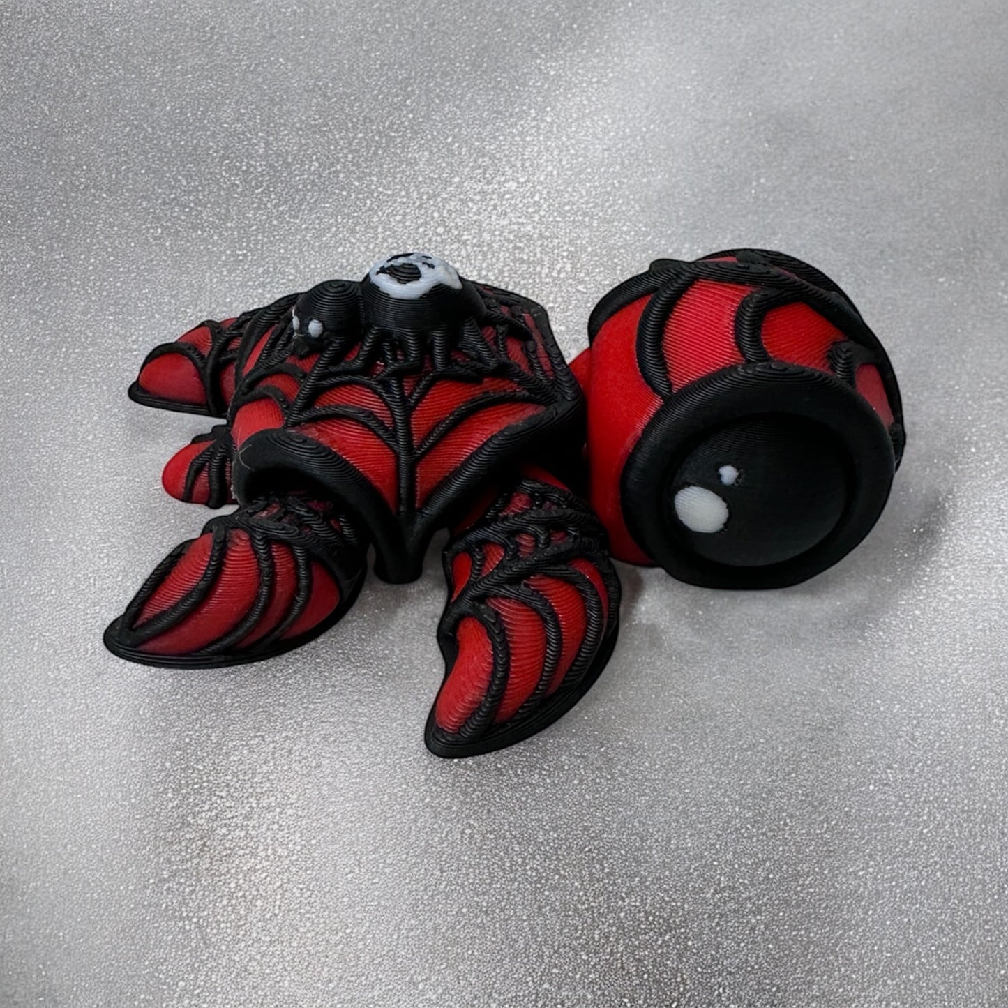 3d printed red and black turtle with a spider on its back on a white background