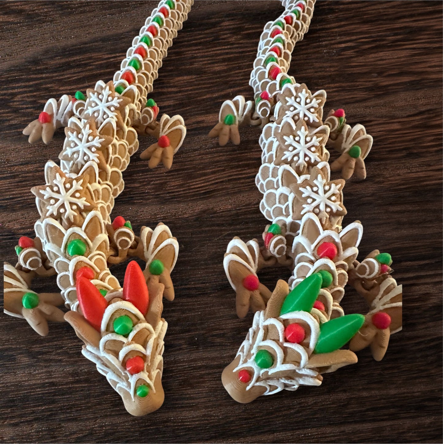 Two, 3D printed dragons designed to look like a gingerbead cookie - brown dragon with white, green and red frosting printed on top