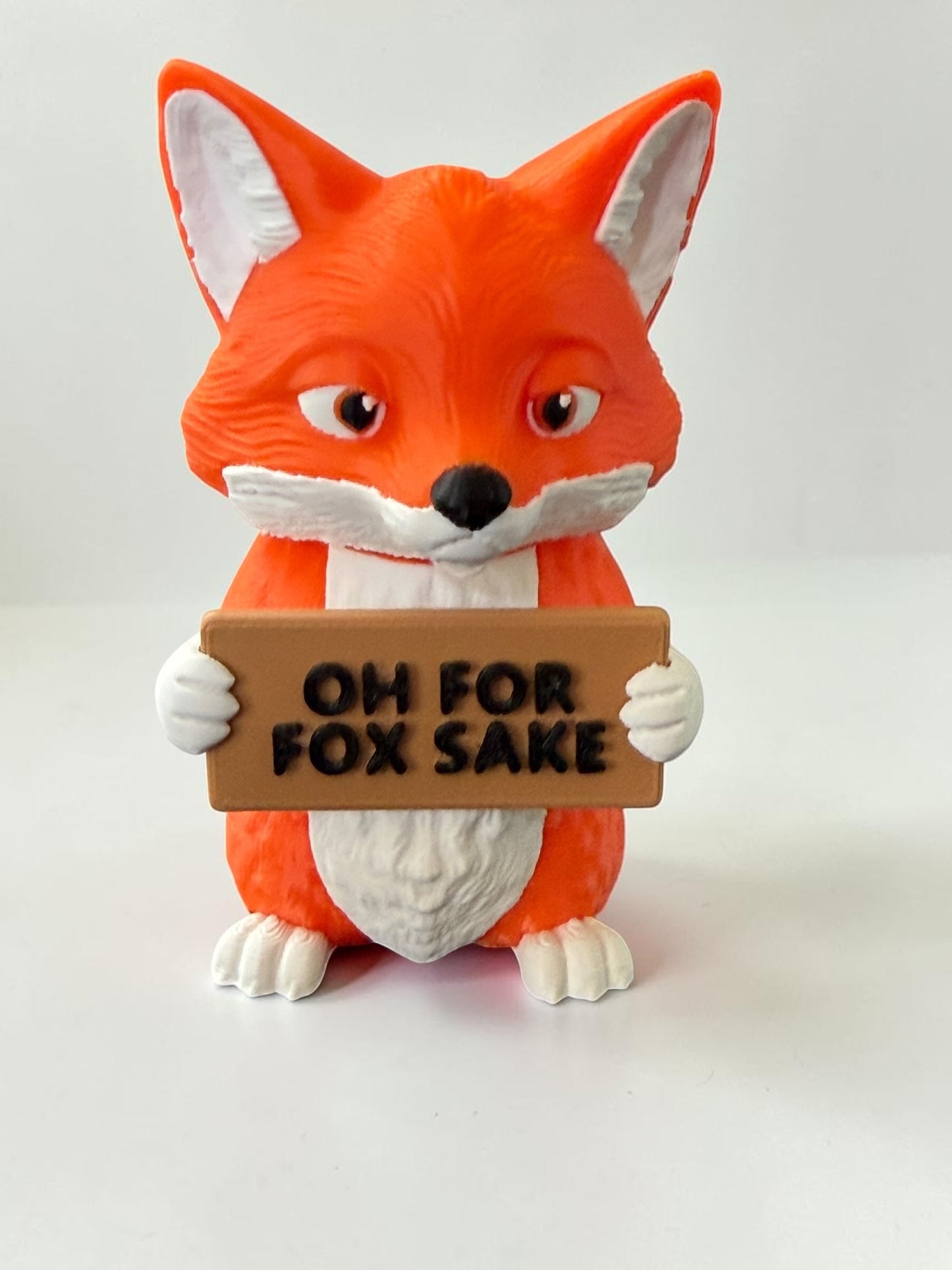 3d printed fox holding a sign that says "Oh for fox sake"