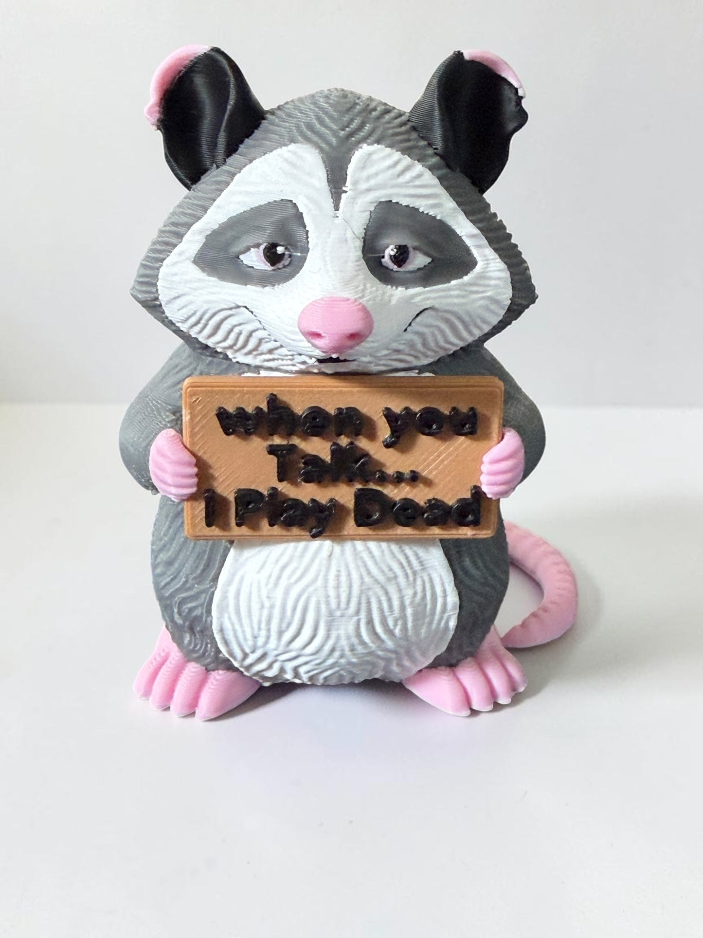 3d printed opossum holding a sign that says "When you talk...I play dead"