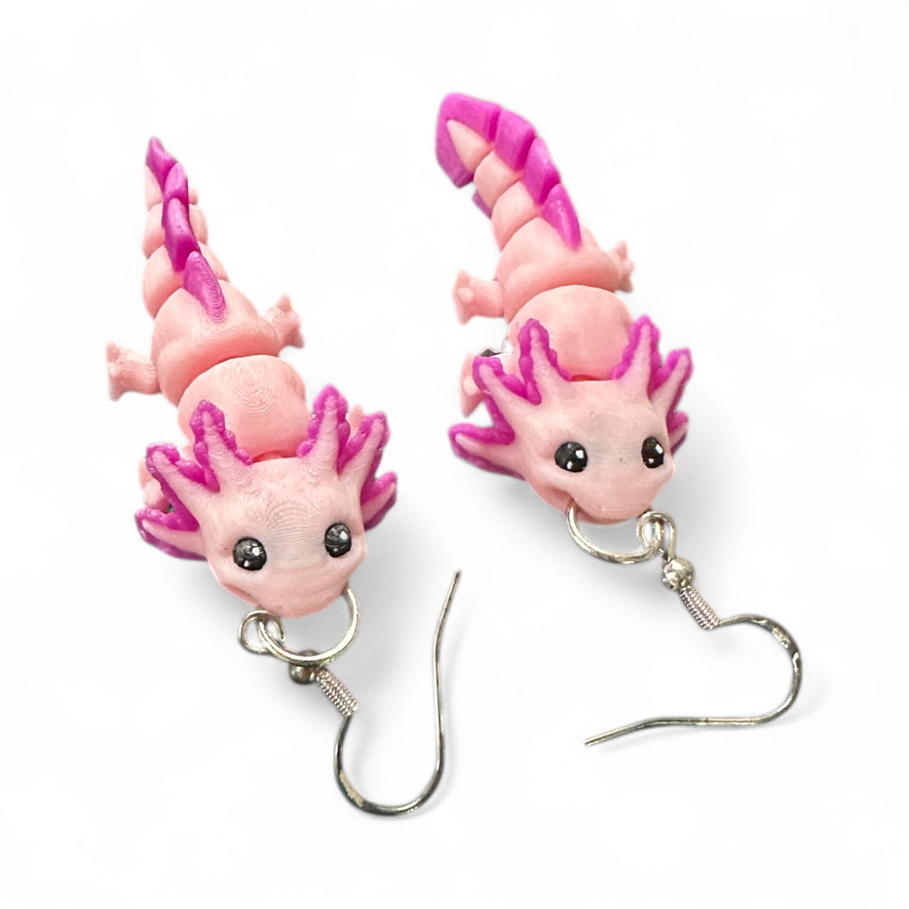 Pair of pink and purple axolotl shaped earrings on a white background