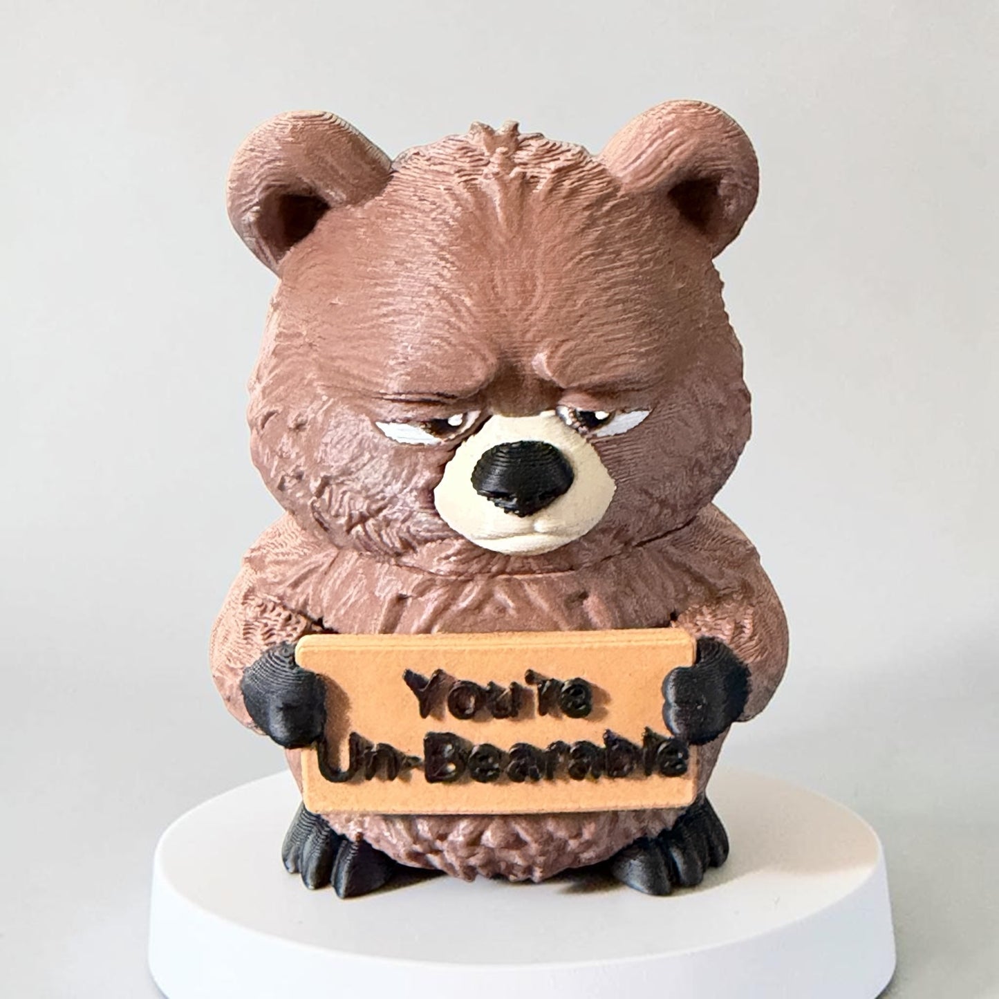 3D Printed bear holding a sign that says "Un-Bearable"