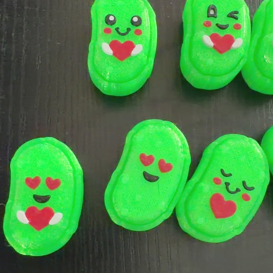 Video of small pickle shaped 3d printed clicker fidgets on a black background.