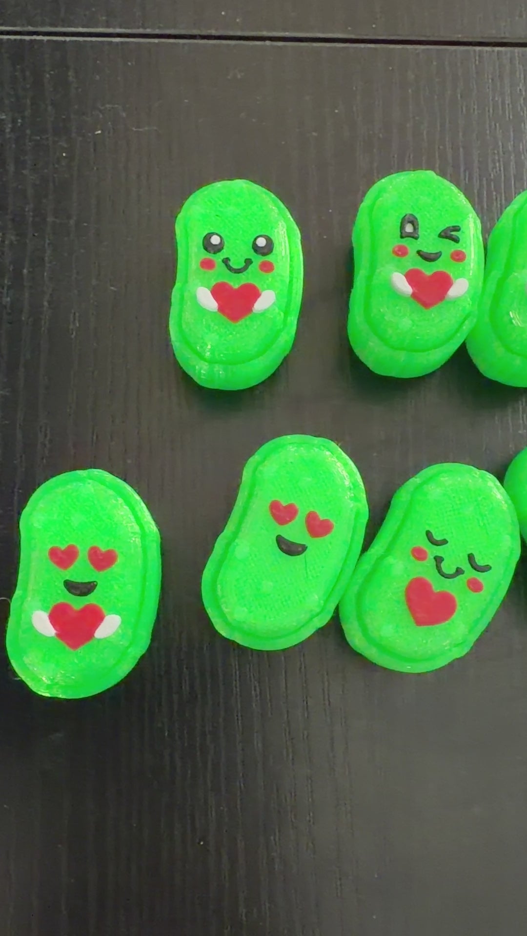 Video of small pickle shaped 3d printed clicker fidgets on a black background.